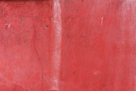 A smooth wall painted in red with some stains and rough textureの写真素材