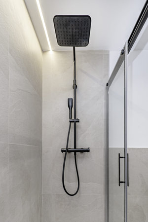 Black steel shower head in a glass-enclosed shower