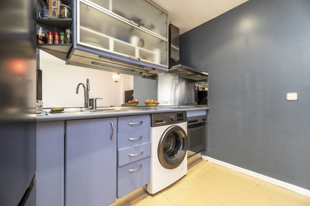 Loft apartment with open kitchen with blue furniture, stoneware floors, gray walls and gray countertopの写真素材