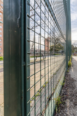 A green metal mesh fence on the perimeter of a basketball court.の写真素材