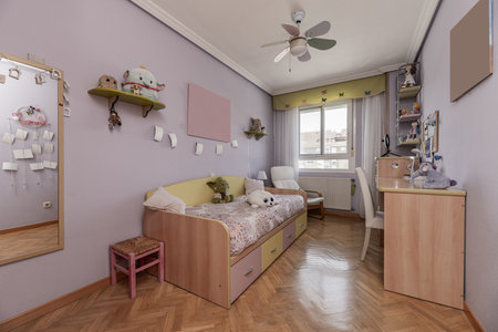 A bedroom with a youth bed with a wooden structure, colorful drawers, an attractive duvet cover and a matching deskの写真素材