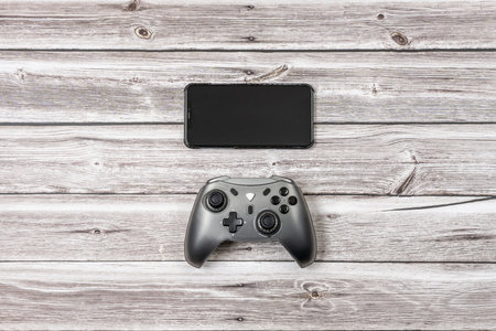 A smartphone and a gamepad on a light wooden tableの写真素材