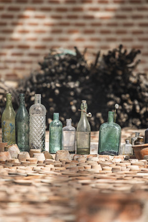 Antique glass bottles of various sizes stacked next to upturned terracotta potsの写真素材