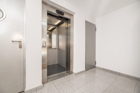 Landing of a house with white painted walls and stainless steel elevator