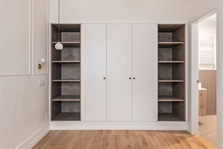 Contemporary bedroom with a high-end wardrobe in a matte white finish and metal handlesの写真素材