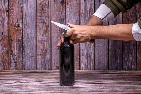 expert hands opening a bottle of wine while the empty glass reflects the warm ambient light