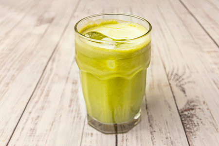 Close-up of a glass of iced matcha tea with herbs and lemon, a moment of summer refreshment
