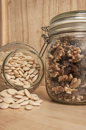Assorted nuts in a clear glass jar on a wooden surfaceの写真素材