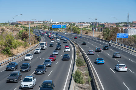 Ring road packed with cars forming a metallic river under the golden light of the urban sunset