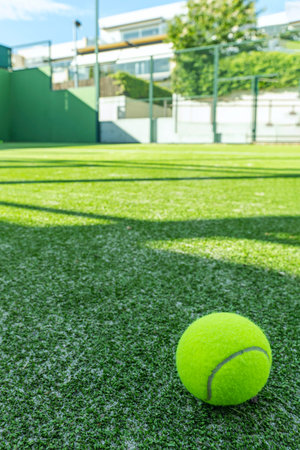 A tennis and padel court with a green artificial grass surface with a tennis ball in the cornerの写真素材