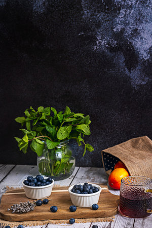 An accidental collision of blueberries on the rim of the white porcelain bowl leaves a small purple trail on the pristine white wooden surfaceの写真素材
