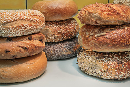 An innovative combination featuring an onion bagel spread with goat cheese, soy- and ginger-marinated salmon, and a topping of sliced avocado and black sesame seeds.の写真素材