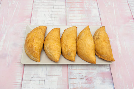A tall stack of small, bite-sized empanadas, perfect for tapas, filled with spicy chorizo or melted...