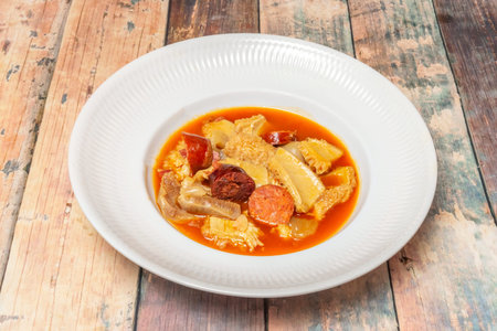 A hearty dish of Madrid-style tripe, featuring chunks of tripe, Burgos black pudding, chorizo, and...