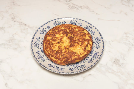 Close-up of a freshly cut slice of potato omelet, showing the juicy interior where the potato and...