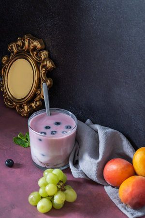 Natural sweetness at its finest: red fruits cut into different shapes (slices, halves, quarters) arranged in a circular pattern around a raspberry and mango smoothieの写真素材