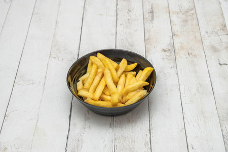 Thinly sliced fries elegantly presented in a white porcelain bowl, accompanied by a sprig of parsley...