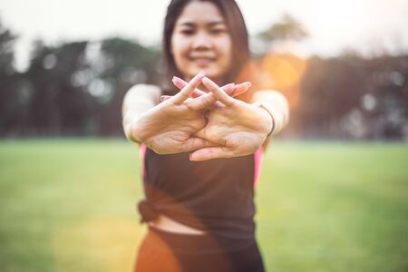 Women warm up before exercising outdoors during the morning hours in the park.の写真素材