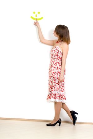 Lady is pointing a smile. On white wall.の写真素材