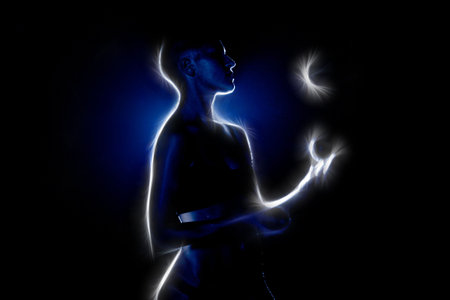 Bald-headed girl juggles on black background.