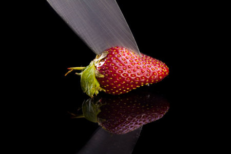 Cook cut strawberries in a glass desk. Isolated on black.の写真素材
