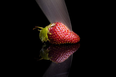 Cook cut strawberries in a glass desk. Isolated on black.の写真素材