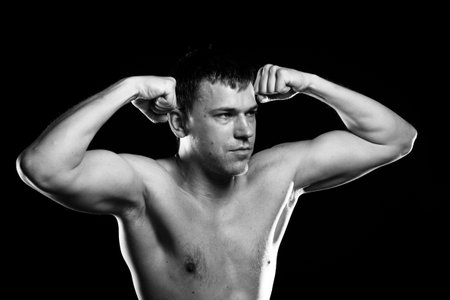 Portrait of handsome muscleman against dark backgroundの写真素材