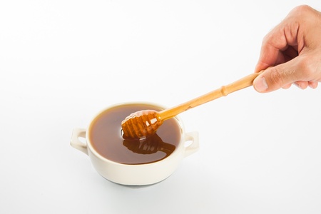 juicy honey in a cup and spoon on white backgroundの写真素材