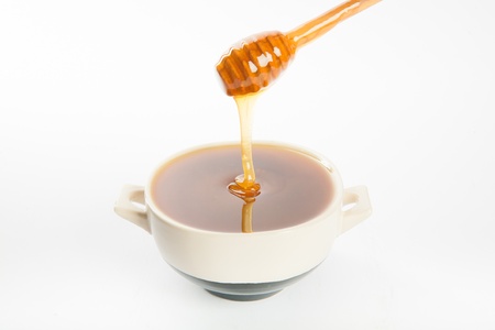 juicy honey in a cup and spoon on white backgroundの写真素材