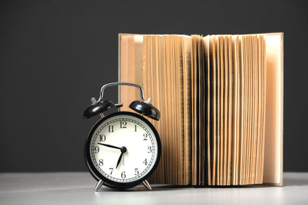 alarm clock with book on black background