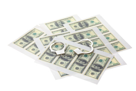 Printed sheets with dollars and handcuffs. Isolated on white.