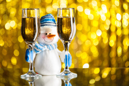 Snowman between glasses of champagne. Golden bokehの写真素材