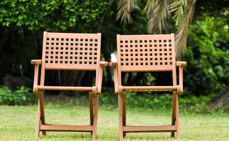 two wooden chairs on lawn green grass, outdoor relaxation, background is gardenの写真素材