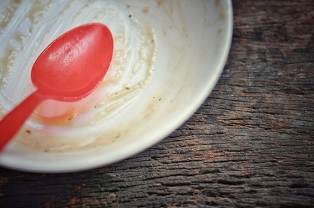 white bowl and red spoon after the finished the meal on the wooden table, dirty bowlの写真素材