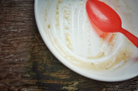 white bowl and red spoon after the finished the meal on the wooden table, dirty bowlの写真素材