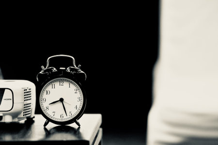 Retro vintage style classic white alarm clock on vintage bedroom background for daylight saving or...