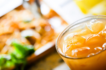 Fresh orange juice in glass with squeezer and oranges on the table with meal in plate background (Selective Focus)の写真素材
