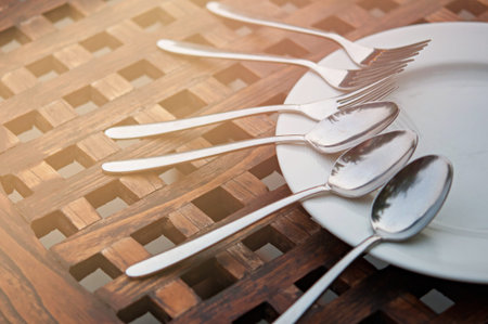 spoon and fork in white plate on wooden table