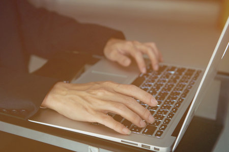 Man's hands on laptop keyboard. side view of human hands, laptop keyboard, notebook on table...