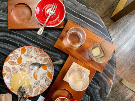 A dirty plate with the remains of jam, dirty Cutlery and a mug of coffee in the restaurant, on a wooden table. Used dishes symbolize the end of lunch or dinner.の写真素材