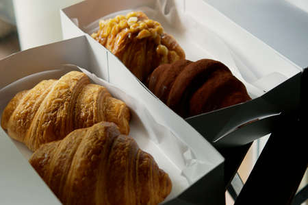 Plain butter croissants in eco friendly compostable disposable food container, plastic-free paper box on the table background. Food in take out or to go packaging theme. (top view, selective focus)の写真素材