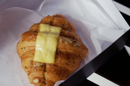 Close up of Freshly baked cheese croissant on a takeaway paper plate in a pastry shop. Soft focus...