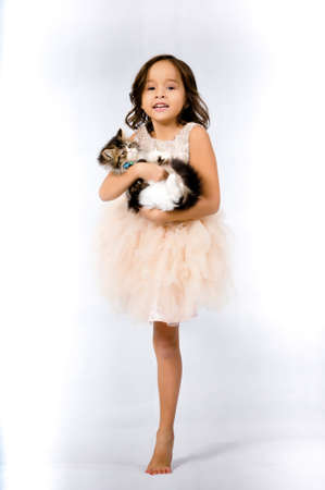 Portrait of happy pretty curly little girl standing and posing over white backgroundの写真素材