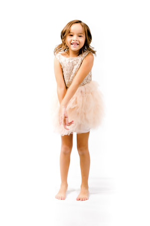 Portrait of happy pretty curly little girl standing and posing over white backgroundの写真素材
