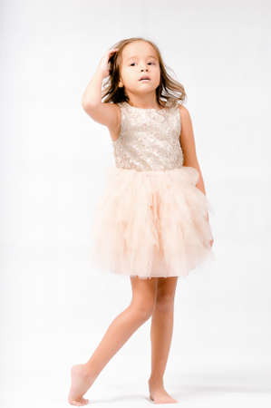 Portrait of happy pretty curly little girl standing and posing over white backgroundの写真素材