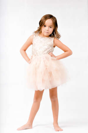 Portrait of happy pretty curly little girl standing and posing over white backgroundの写真素材