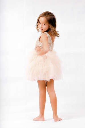 Portrait of happy pretty curly little girl standing and posing over white backgroundの写真素材