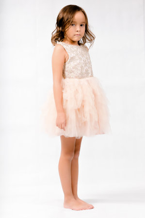 Portrait of happy pretty curly little girl standing and posing over white backgroundの写真素材
