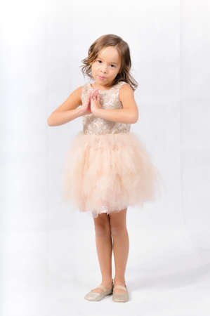 Portrait of happy pretty curly little girl standing and posing over white backgroundの写真素材