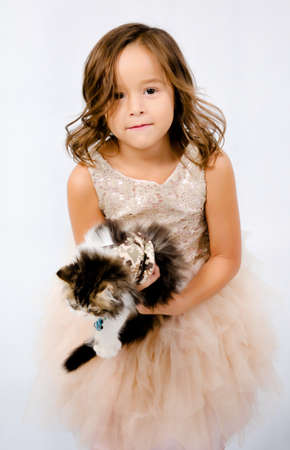 Portrait of happy pretty curly little girl standing and posing over white backgroundの写真素材